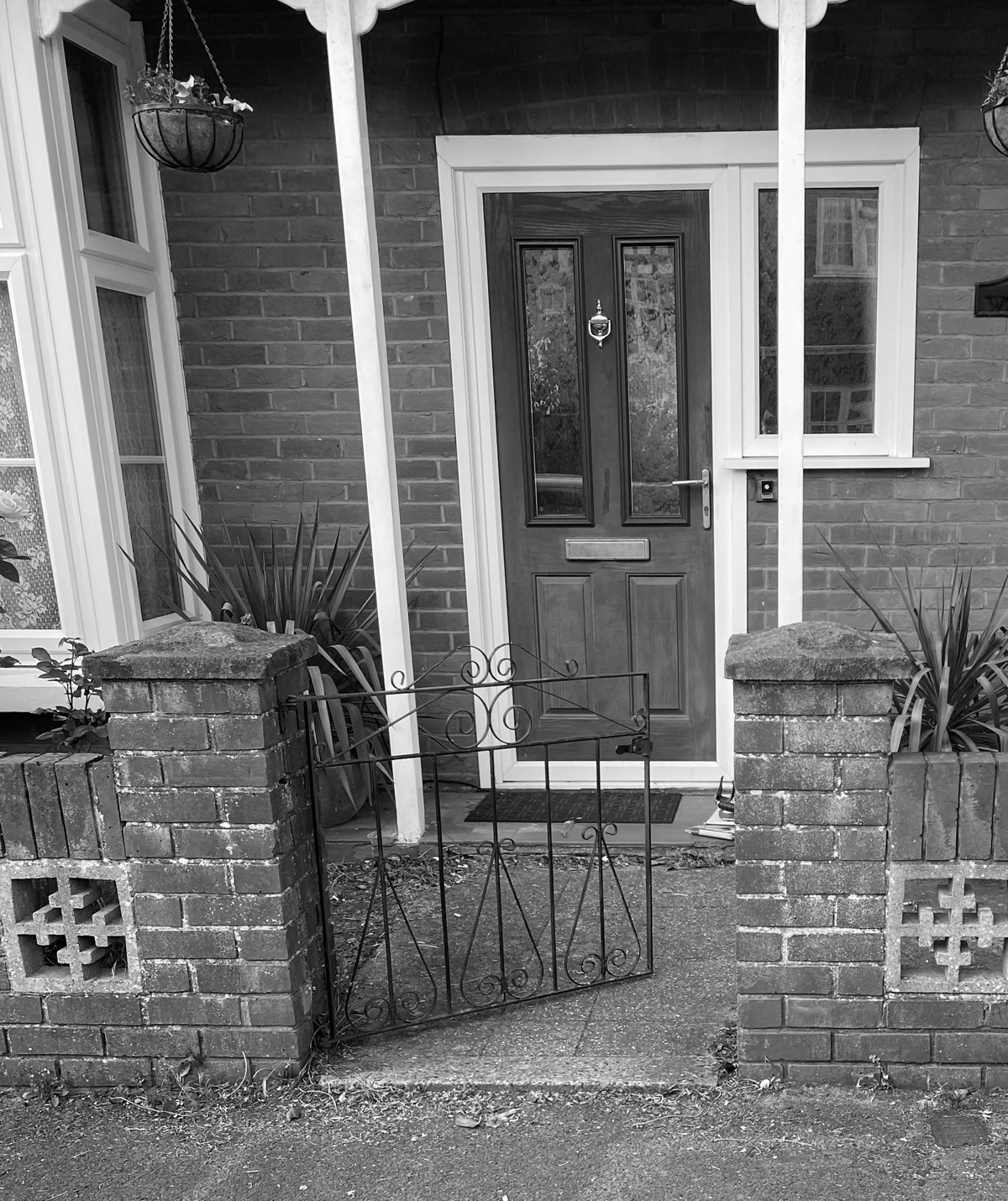 A black and white image of a concrete path leading to a front door